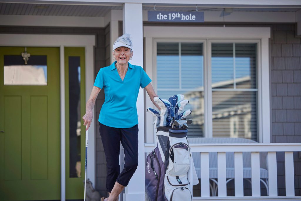 Lutheran Life Villages Resident Louise smiling in front of the "19th hole"